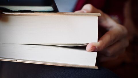 Dickes Buch Eine Hand hält eine Stelle im Buch fest