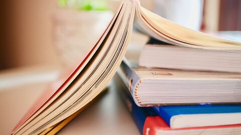 Bücher Bücherstapel, das oberste Buch liegt aufgeschlagen mit dem Rücken nach oben