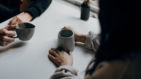 Besuch Zwei Menschen sitzen an einem Tisch und trinken Kaffee
