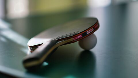 Tischtennisschläger- und ball auf einem Tisch. 