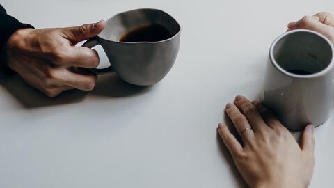 Kaffee trinken Zwei Personen trinken Kaffee an einem weißen Tisch.