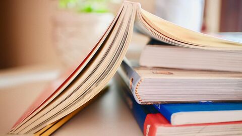 Bücherstapel, das oberste Buch ist aufgeschlagen.