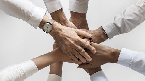 Vier Personen legen ihre Hände übereinander.