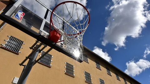 Basketballkorb Blick von unten auf einen Basketballkorb, im Hintergrund ein Gebäude der JAE Gelnhausen und Himmel mit Wolken.